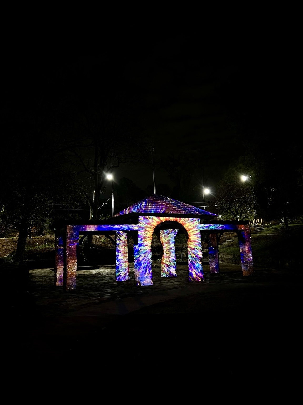 A gazebo illuminated with colorful projection mapping at night
