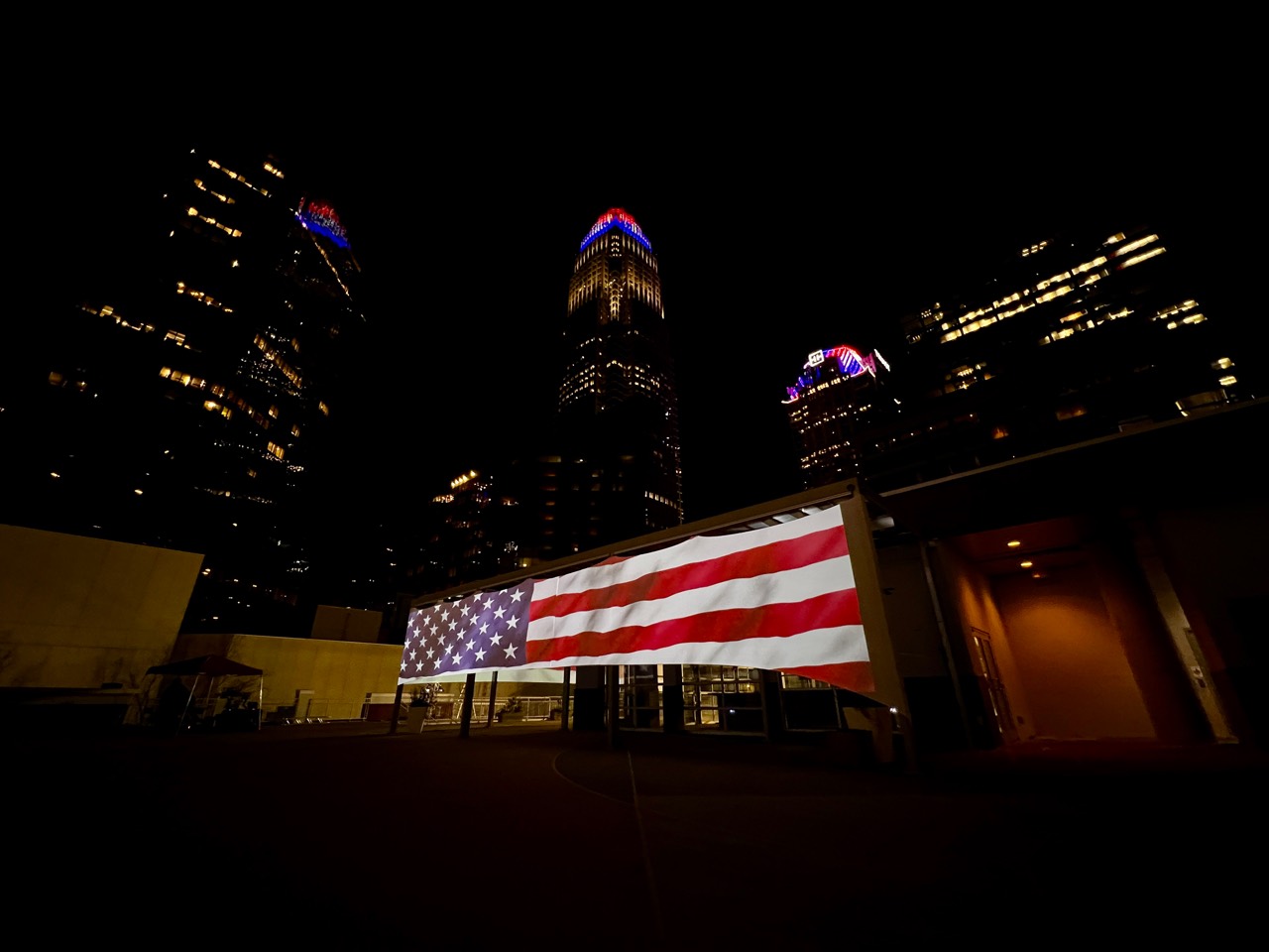 An American flag projected across a building beneath the city skyline