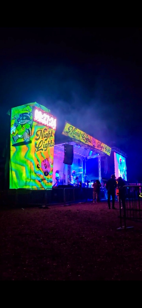Colorful projection visuals framing an outdoor festival stage at night