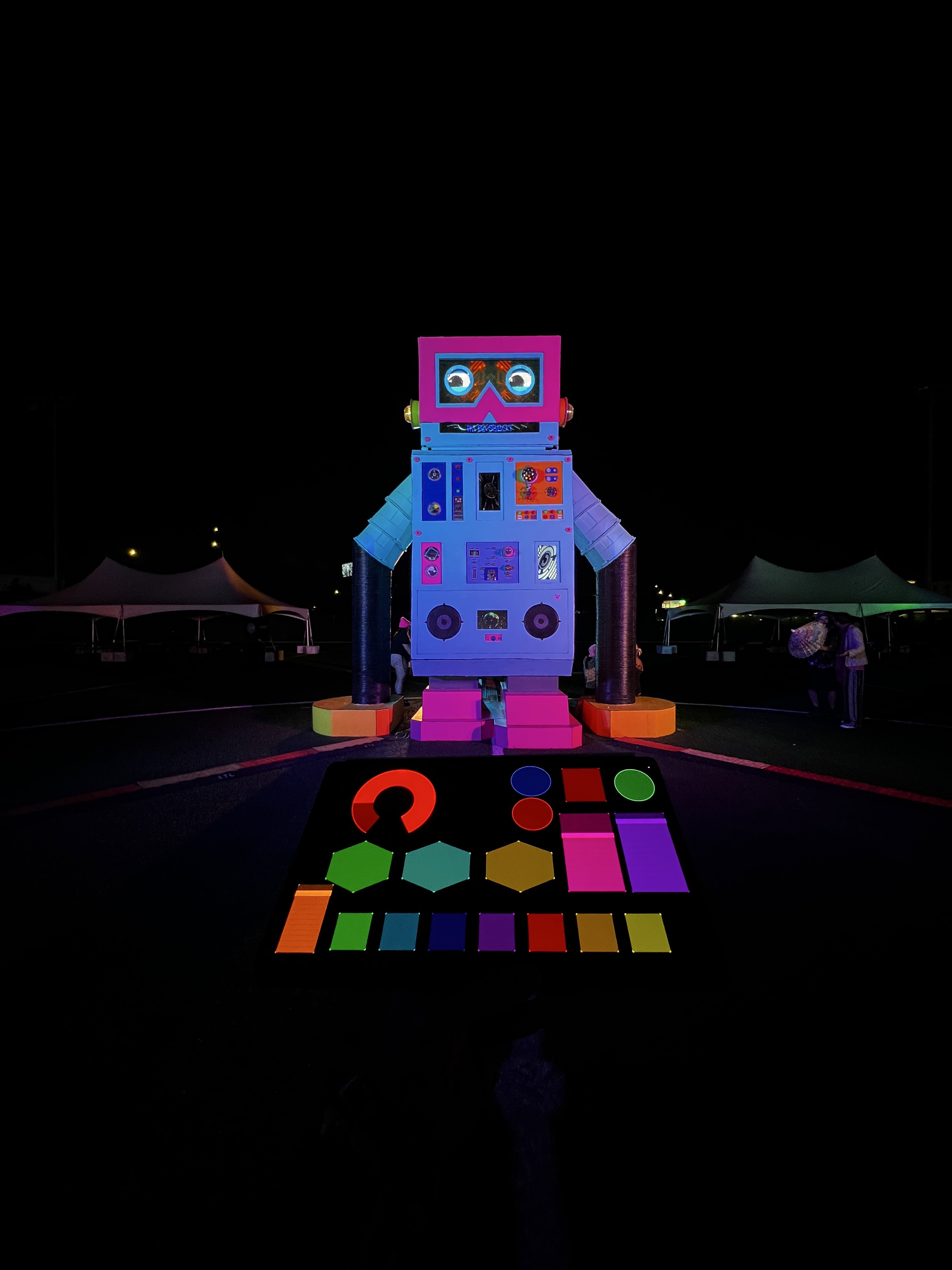 A colorful robot installation with an illuminated control panel at night