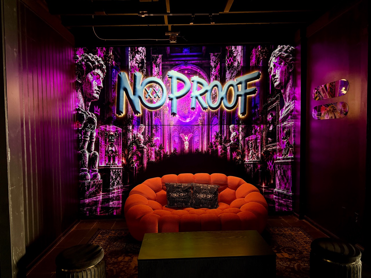 Purple architectural visuals behind the No Proof lounge seating
